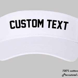 May include: White visor with a pre-curved brim. The visor has black text that says "CUSTOM TEXT".