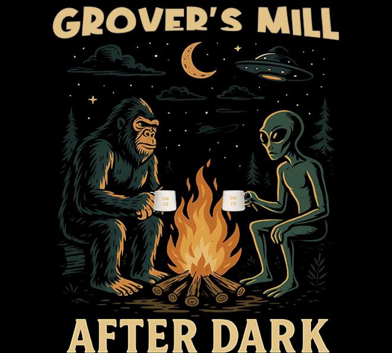 Puede incluir: Camiseta negra con un dise&ntilde;o gr&aacute;fico de un Bigfoot y un extraterrestre sentados junto a una fogata, cada uno con una taza. El texto "GROVER'S MILL AFTER DARK" est&aacute; arqueado arriba y abajo. Un OVNI y una luna creciente en el fondo.