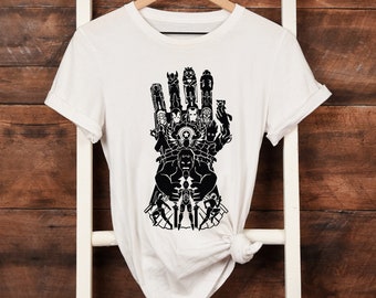 May include: White t-shirt featuring a black graphic of the Avengers characters forming the shape of Thanos's gauntlet.