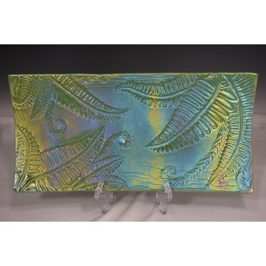May include: A rectangular serving tray with a green and blue iridescent glaze. The tray features an embossed fern leaf design.