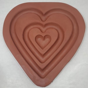May include: A terracotta heart-shaped mold with five concentric heart-shaped depressions.