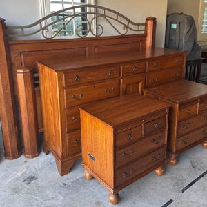 May include: A bedroom furniture set in a warm, medium-brown finish. The set includes a bed frame with a decorative metal headboard, a dresser with multiple drawers, and two nightstands. The wood grain is visible.