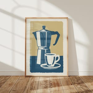 May include: A framed wall art print featuring a stylized illustration of a blue moka pot and a white coffee cup on a saucer. The design uses a color palette of muted tan, deep blue, and white, presented in a rectangular vertical orientation.