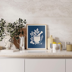 May include: A framed rectangular wall art print featuring a dark blue background with a white graphic illustration of a mortar and pestle surrounded by sprigs of herbs, garlic cloves, and peppercorns, centered in a thin light-colored wooden frame.