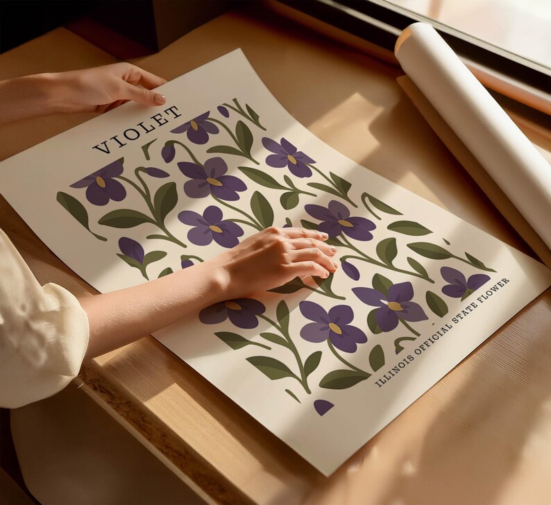A person's hands are holding a poster with a floral design featuring purple flowers and green leaves.