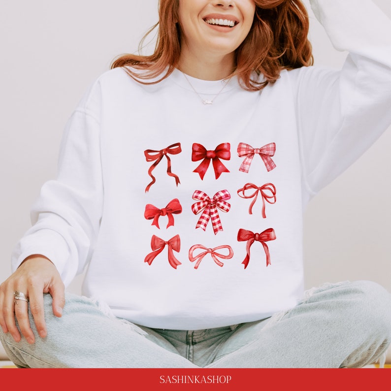 May include: White sweatshirt with a red bow pattern. The bows are in various styles and sizes. The text "SASHINKASHOP" is at the bottom of the sweatshirt.