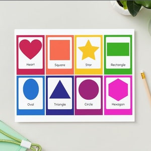 May include: A set of nine colourful flashcards featuring different shapes, including a heart, square, star, rectangle, oval, triangle, circle, and hexagon. Each card has the name of the shape printed below the image.