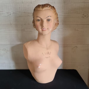 Può includere: Un busto di manichino vintage in gesso con viso e capelli dipinti. Il busto è etichettato "LUBE PARIS" sul petto.