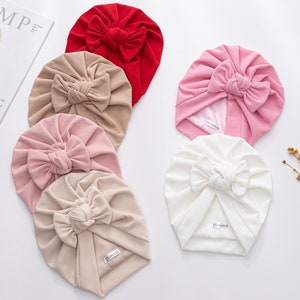 Puede incluir: Cinco diademas de turbante en diferentes colores: rojo, beige, rosa, blanco y beige. Cada diadema tiene un gran lazo en la parte superior.