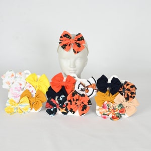 Könnte beinhalten: Ein Set mit 10 bunten Haarbändern mit verschiedenen Mustern, darunter Blumen-, Tier- und geometrische Designs. Die Schleifen sind an elastischen Haarbändern befestigt.