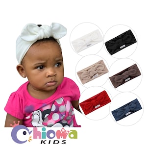 May include: A young girl wearing a pink shirt with a Minnie Mouse design is wearing a white knotted headband. The image also shows nine different colors of knotted headbands, including white, black, beige, brown, red, and blue.