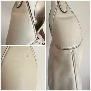 May include: A white leather handbag with a flap closure and a brown leather strap. The bag has a slightly distressed look and is made of high-quality leather.