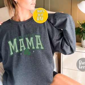 May include: Dark grey sweatshirt with the text "Irish Lucky Mama" in green and white lettering with a green shamrock graphic.