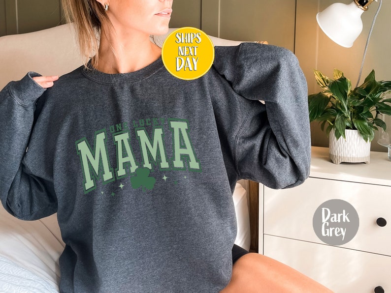 May include: Dark grey sweatshirt with the text "Irish Lucky Mama" in green and white lettering with a green shamrock graphic.