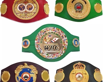 Könnte beinhalten: Fünf verschiedene Boxweltmeistergürtel mit verschiedenen Farben und Designs. Die Gürtel sind aus Leder und haben Metallakzente. Die Gürtel zeigen die Logos der International Boxing Organization (IBO), des World Boxing Council (WBC), der World Boxing Organization (WBO) und anderer Organisationen.