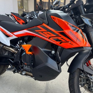 Könnte beinhalten: Nahaufnahme eines orange-schwarzen Motorrads mit dem Schriftzug "HERTHAMMF" an der Seite. Das Motorrad hat einen schwarzen Sitz und einen schwarzen Auspuff.