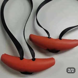 May include: Two red rubber handles with black straps. The handles are shaped like a crescent moon and have two holes on each side. The straps are adjustable and can be used to attach the handles to a variety of objects.