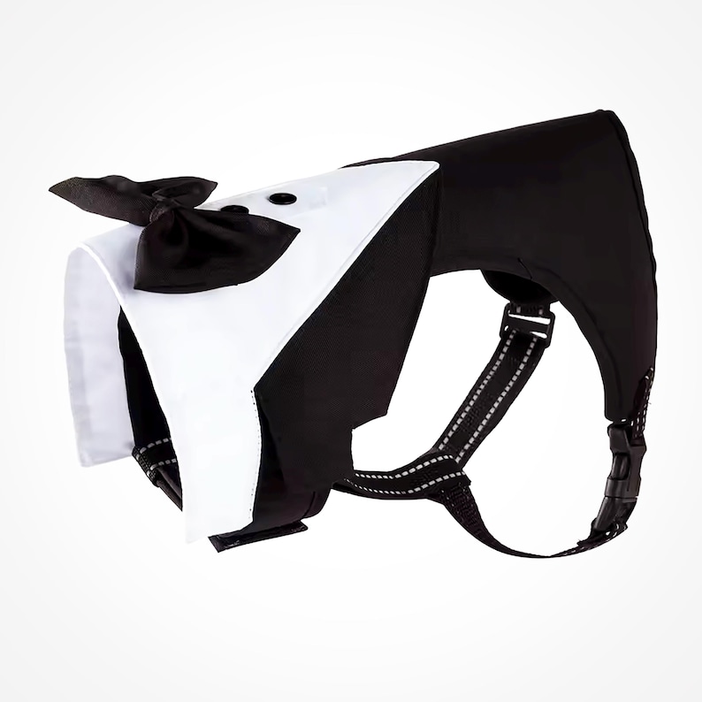 A black and white dog harness with a tuxedo-style bow tie. The harness has adjustable straps and a buckle closure.