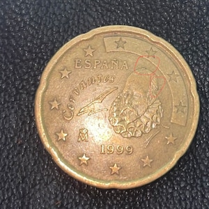 以下が含まれることがあります： スペインの1セント硬貨で、ブロンズ色をしています。縁には「ESPAÑA」と「Cervantes」の文字が刻まれています。硬貨にはスペインの作家、ミゲル・デ・セルバンテスの肖像が描かれており、肖像の下には「1999」という年号が刻まれています。