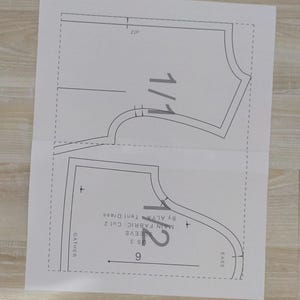 May include: A black and white sewing pattern for a tent dress with instructions for cutting the fabric and sewing the sleeves. The pattern includes measurements in inches.