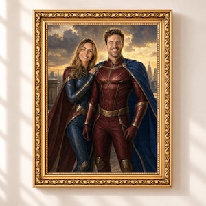 May include: A framed portrait featuring a smiling couple dressed in superhero costumes. The person on the left wears a dark blue suit with a maroon cape, while the person on the right wears a maroon suit with a blue cape. The background shows a city skyline under a cloudy, golden sunset sky, all enclosed in an ornate, metallic gold frame.