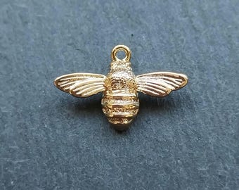 May include: A gold-coloured bee charm with detailed wings and body segments. The charm has a loop at the top for attaching to jewellery or other crafts. The bee is a symbol of nature and can be used for various DIY projects.