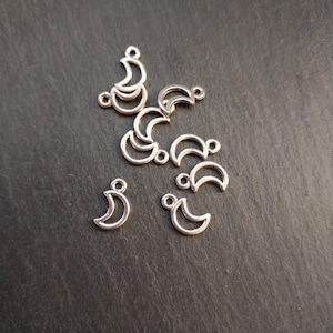 以下が含まれることがあります： ジュエリーやその他のクラフトに付けるためのループが上部にある、銀色の金属製の三日月形のチャームのグループです。