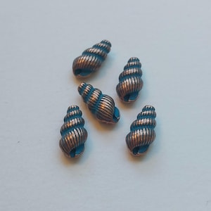 May include: Five copper-colored spiral seashell beads with blue accents. The beads have a ridged texture and a small opening at the base. These decorative beads are ideal for jewelry making or craft projects.