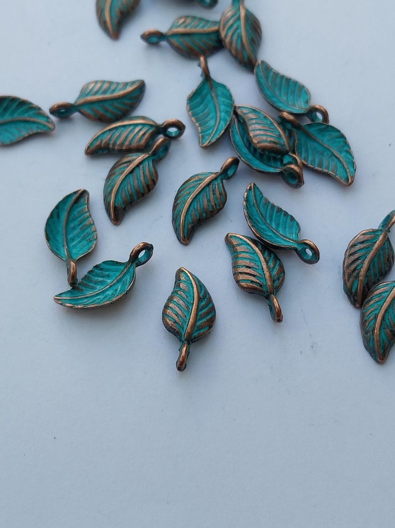 Peut inclure: Plusieurs petits breloques en forme de feuilles. Chaque breloque pr&eacute;sente une surface de couleur teal avec des veines de couleur bronze et une boucle pour l'attache. Ces breloques d&eacute;coratives sont id&eacute;ales pour la cr&eacute;ation de bijoux ou les projets d'artisanat.