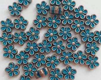 May include: A collection of small, five-petaled flower beads featuring a metallic copper-toned finish and a vibrant turquoise enamel center. Each bead has a central hole for stringing, with a consistent floral shape and a rustic, weathered texture.