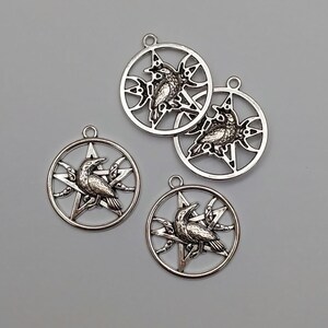 May include: Four silver-toned metal pendants, each featuring a circular frame enclosing a five-pointed star and a crescent moon. A detailed raven is depicted perched in the center of each star. Each pendant includes a small loop at the top.