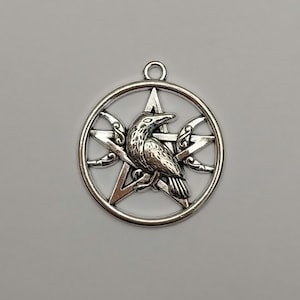 May include: Silver pendant with a raven design, set within a pentagram and circular frame. Crescent moon symbols are incorporated. The pendant has a loop for a chain. Ideal for jewellery or craft projects, this piece is a striking, symbolic accessory.