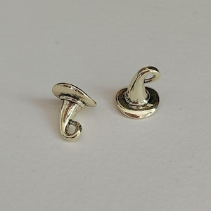 May include: Two small, gold-colored witch hat charms. One hat is lying on its side, while the other is upright. The hats have a classic pointed shape with a wide brim and a curled tip, perfect for jewelry making or crafting projects.