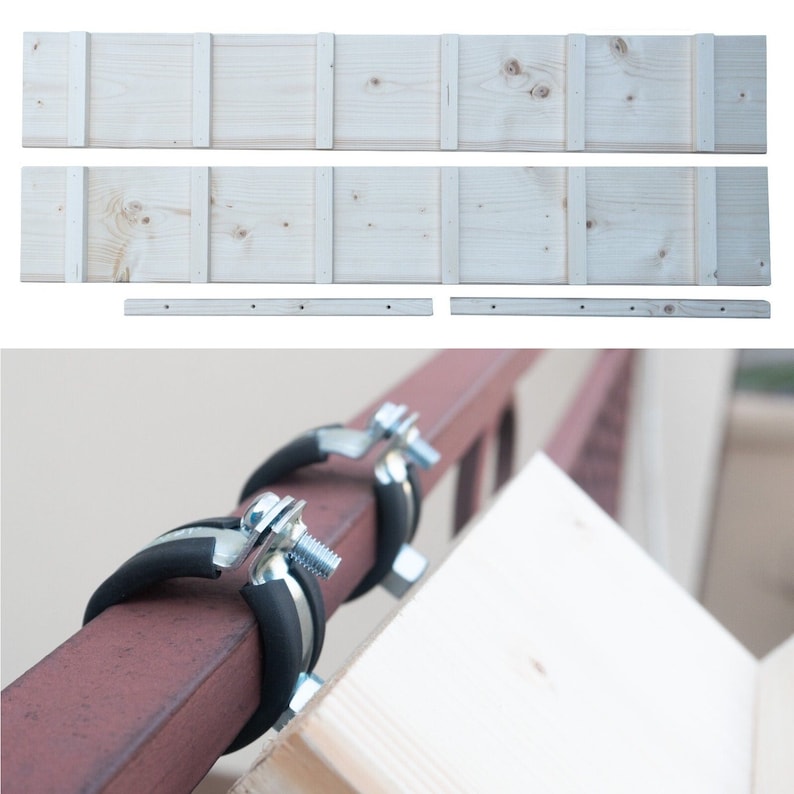 May include: Two metal clamps with rubber inserts are attached to a brown metal pipe. A light wood plank is attached to the clamps.