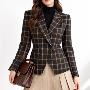May include: A black and gold plaid blazer with a double-breasted design. The blazer is paired with a tan pleated skirt and a brown leather satchel. The outfit is completed with a black turtleneck.