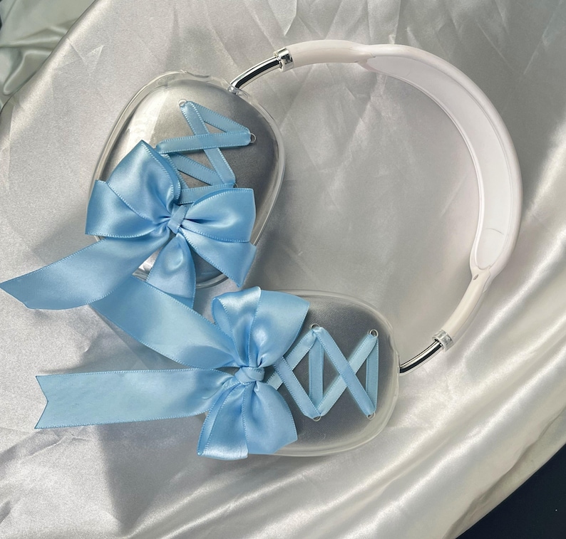 Puede incluir: Un par de auriculares blancos con lazos azules claros en cada auricular. Los lazos est&aacute;n hechos de cinta de sat&eacute;n y est&aacute;n atados en un nudo.