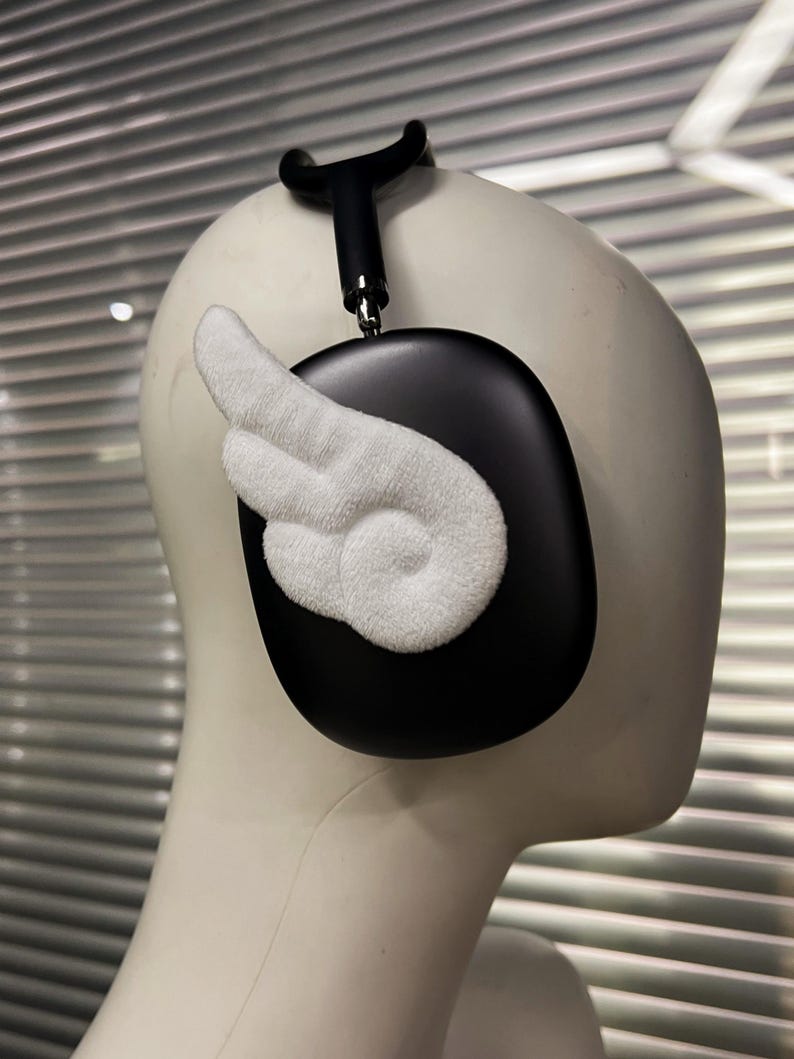 May include: Black over-ear headphones with a white, textured wing design attached to the ear cup. The headphones are on a mannequin head. The headband and ear cup are black.