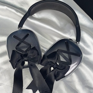 Puede incluir: Auriculares transparentes con lazos negros en cada auricular. Los auriculares tienen una diadema negra.