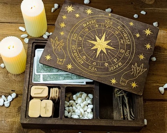 May include: A wooden box with a lid that opens to reveal a circular divination board with gold zodiac symbols and the words "Yes", "Maybe", and "Rephrase No". The box also contains a set of small wooden blocks with numbers and a compartment filled with white stones.