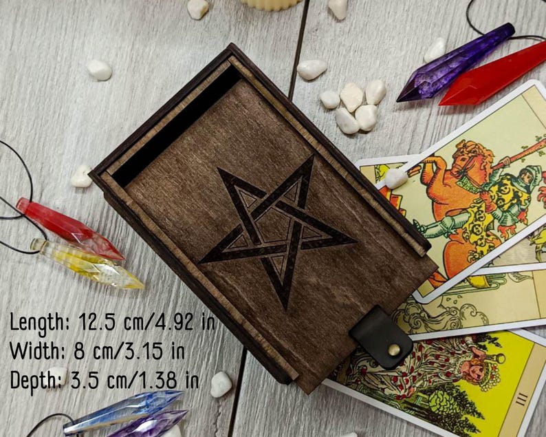 May include: A wooden box with a pentagram design on the lid. The box is 12.5 inches long, 8 inches wide, and 3.5 inches deep. It is made of dark wood and has a leather strap closure.