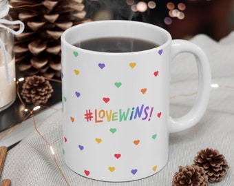 May include: White ceramic coffee mug with a rainbow #LOVEWINS! design and a scattering of colorful hearts.