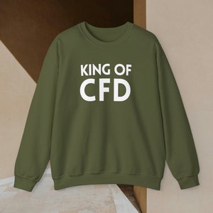 Könnte beinhalten: Ein grüner Pullover mit dem Aufdruck "KING OF CFD" in Weiß auf der Vorderseite.