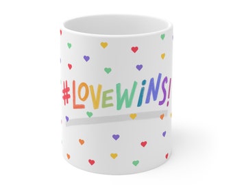 May include: White ceramic mug with a rainbow colored hashtag that says "#LOVEWINS!" and a white background with scattered rainbow hearts.