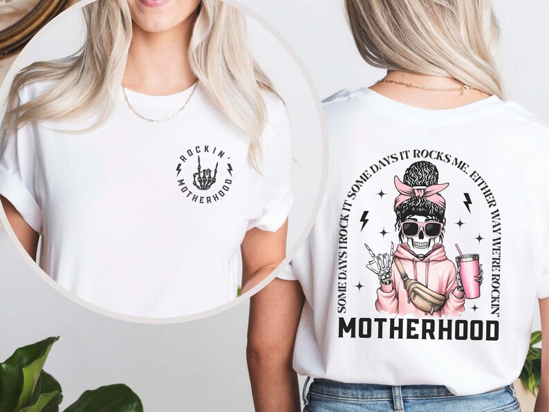 K&ouml;nnte beinhalten: Wei&szlig;es T-Shirt mit einem schwarz-wei&szlig;en Grafikdruck einer Skeletthand, die ein Rock'n'Roll-Zeichen macht, mit dem Text "Rockin' Motherhood" auf der Vorderseite. Die R&uuml;ckseite des Shirts zeigt eine schwarz-wei&szlig;e Grafik einer Skelettfrau mit rosa Haaren und Sonnenbrille, die einen rosa Hoodie tr&auml;gt und eine rosa Tasse h&auml;lt. Der Text "Some days I rock it, some days it rocks me. Either way we're rockin' Motherhood" ist um die Grafik herum gedruckt.