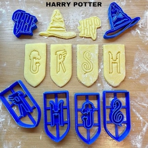 Könnte beinhalten: Eine Sammlung blauer Kunststoff-Ausstecher und gebackener Kekse in verschiedenen Formen. Die Formen umfassen einen Zaubererhut, einen Blitz und Buchstaben. Der Text "HARRY POTTER" ist oben im Bild zu sehen.