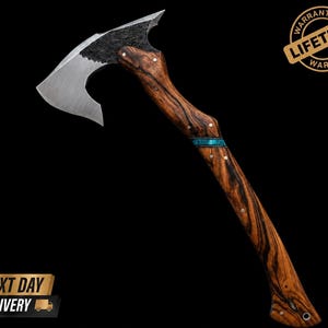 May include: A hand axe with a polished steel blade and a textured black metal head transition. The handle is crafted from dark brown wood with prominent black grain patterns, featuring a turquoise inlay band and small metal pins throughout.