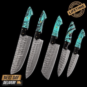 May include: A set of five kitchen knives with hammered metal blades and marbled teal and black resin handles. Each handle features a black bolster and a gold-toned circular rivet. The blades have a textured, dimpled finish and sharp edges.