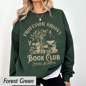 May include: Forest green sweatshirt with a graphic print of a skull, potion bottles, and books. The text reads "Professor Orion's Book Club Zodiac Academy".