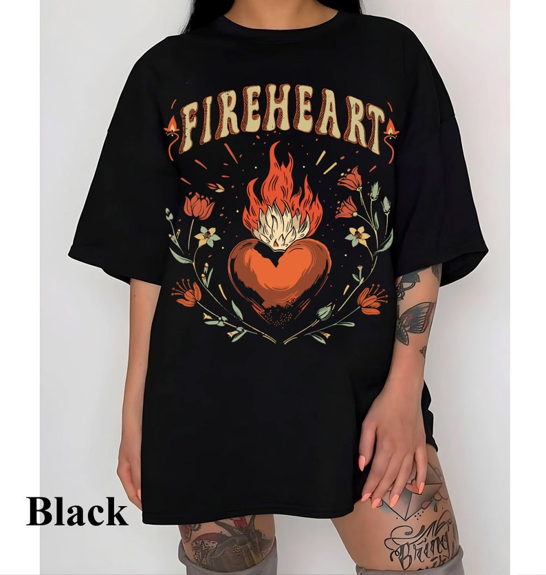Puede incluir: Camiseta negra de gran tama&ntilde;o con un estampado gr&aacute;fico de un coraz&oacute;n en llamas rodeado de flores y el texto "FIREHEART".