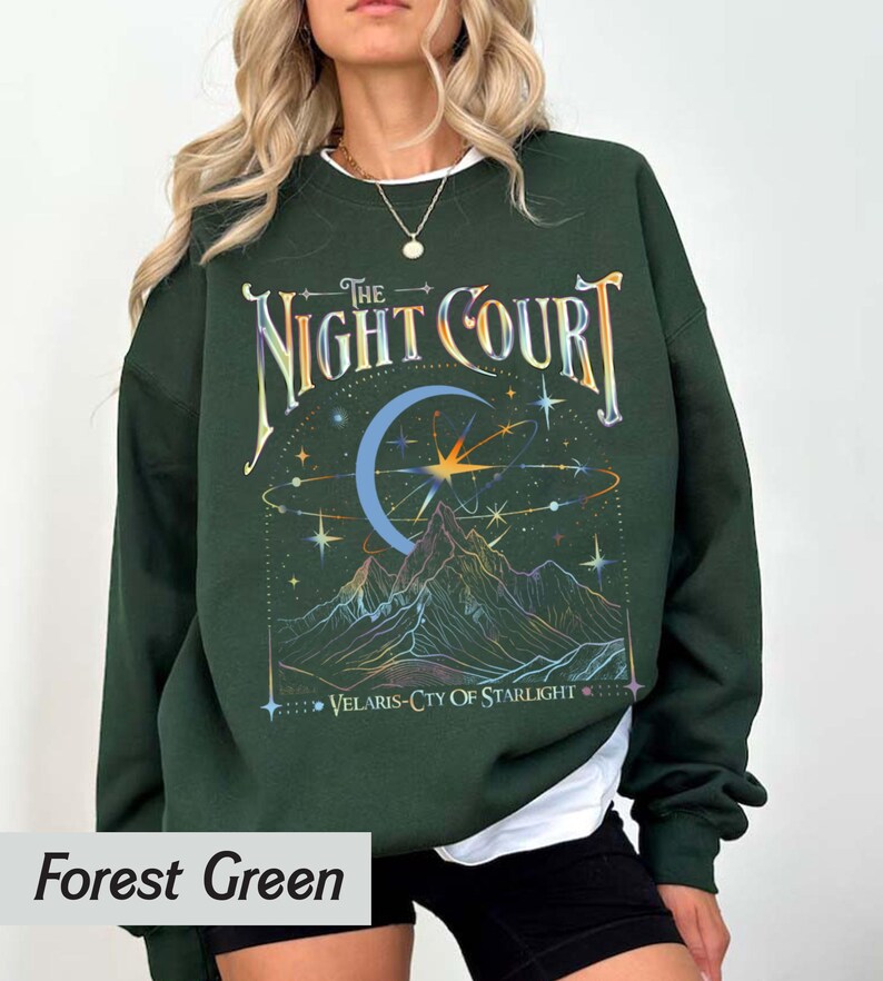 Op de afbeelding: Bosgroen sweatshirt met een grafische print van een halve maan, sterren en bergen. De tekst "The Night Court" en "Velaris-City of Starlight" staat op het sweatshirt gedrukt.